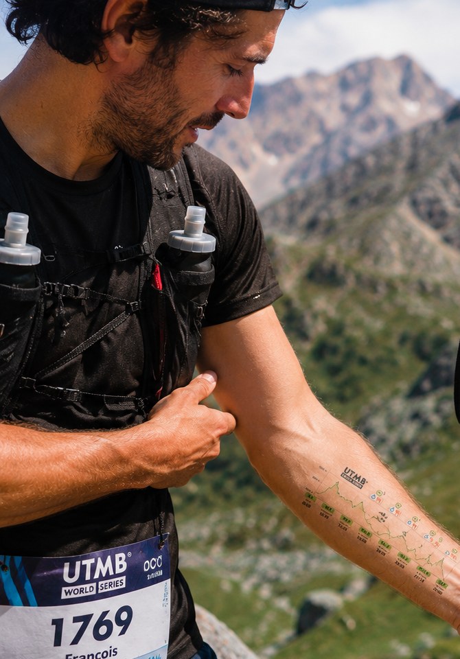 Runner checking their SeeURace race guide on their forearm during a mountain race